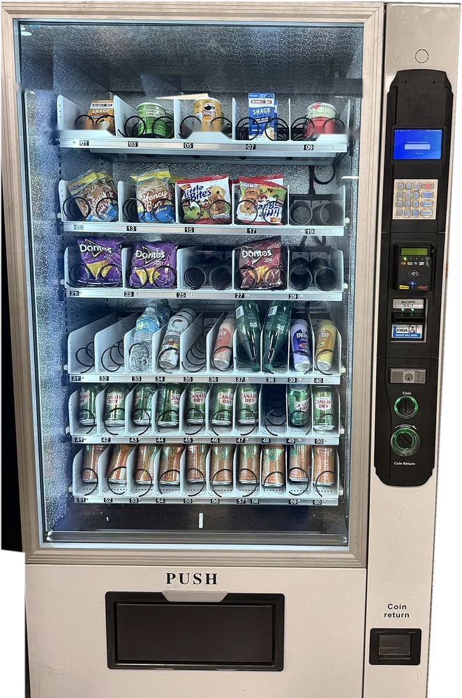 Glass-front combo machine stocked with chips, cookies, water, energy drinks and ginger ale, with a card reader and touchscreen.